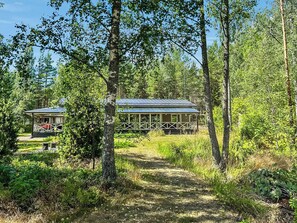 A cabin with a porch and a covered walkway, surrounded by dense forest. - Villa blombacka by Interhome (Loviisa)