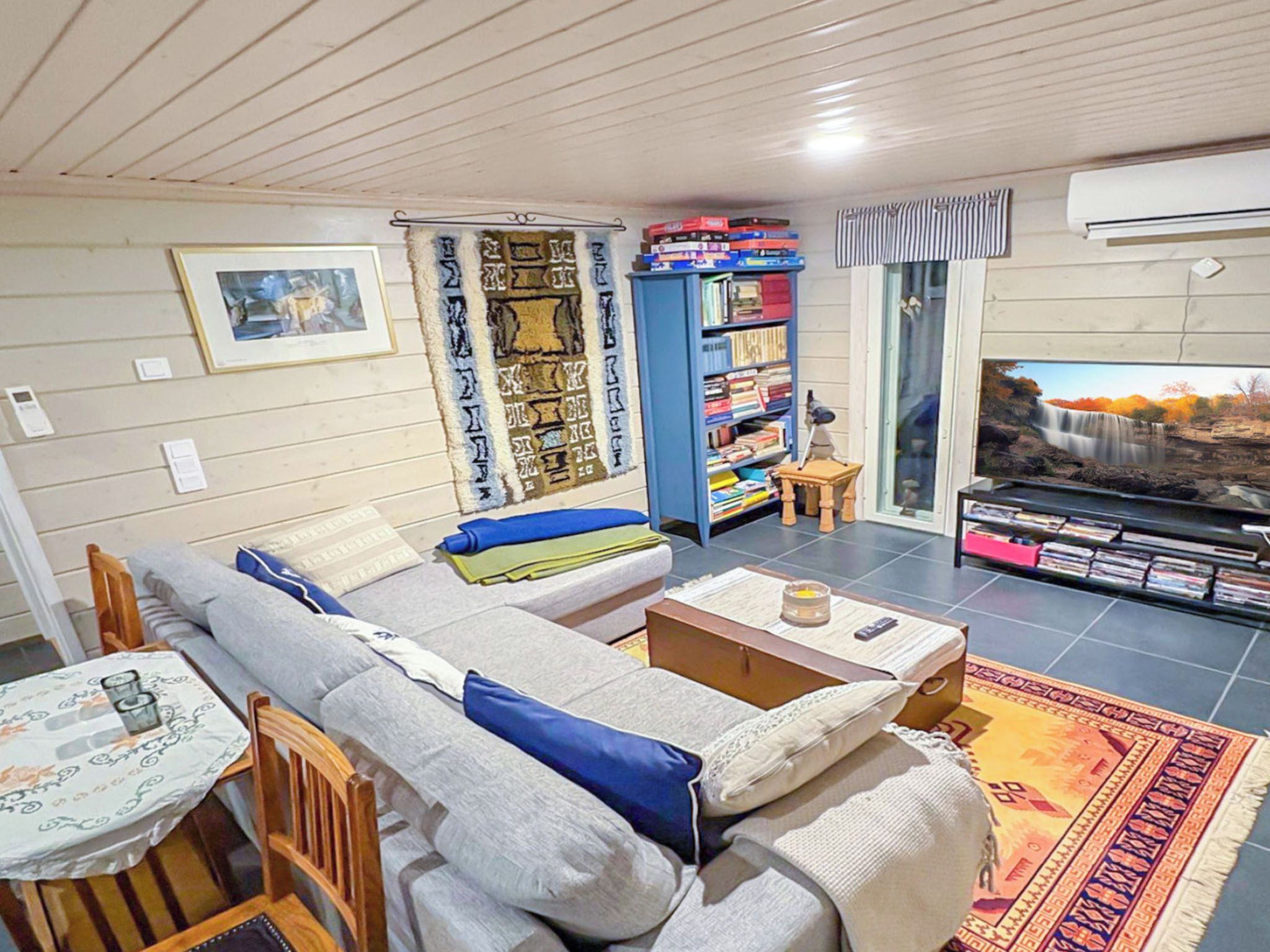 A living room with a sofa, a small table, a bookshelf, and a television.