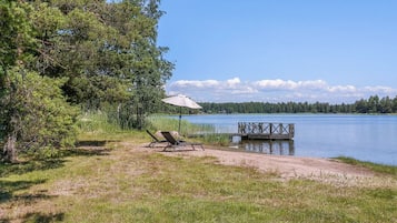Et sølandskab med en træbro, en strandstol og en parasol.