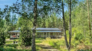 Een chalet met een veranda en een klein terras, omgeven door dicht bos.