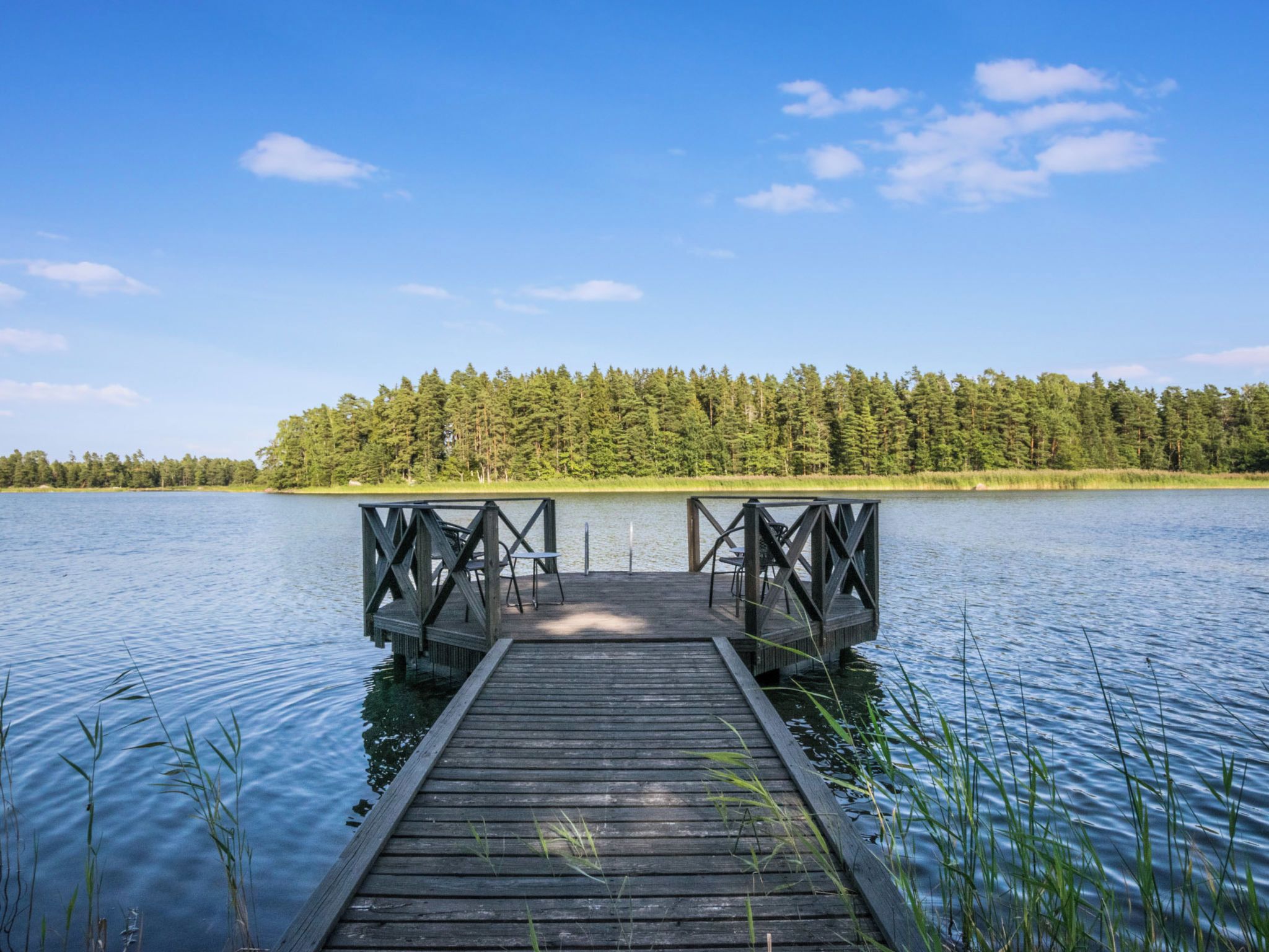 Puinen laituri, joka ulottuu tyynelle järvelle, ja taustalla näkyy metsäinen rantaviiva.