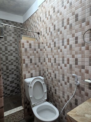 A bathroom with a tiled shower, a toilet, and a sink. - La Aldea (Lapu-Lapu)