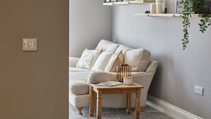 A cozy living room with a beige sofa, a wooden side table, and a hanging plant. - Host & Stay | Sea Breeze (Amble)