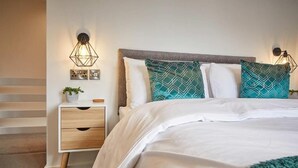Quarto com cama, mesas de cabeceira e iluminação fixa na parede.
