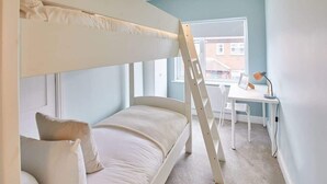 A bunk bed with a ladder, a desk with a chair, and a window with a view of buildings. - Host & Stay | Ings Lane (Saltburn-by-the-Sea)