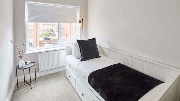 A bedroom with a bed, a window, a radiator, and a small table with a vase. - Host & Stay | Ings Lane (Saltburn-by-the-Sea)