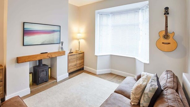A living room with a fireplace, a sofa, a guitar, and a painting. - Host & Stay | Ings Lane (Saltburn-by-the-Sea)