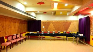 A conference room with a long table, chairs, and a stage area. - Hotel Matrix Inn (Rajgurunagar)