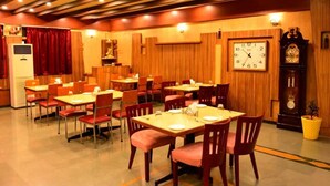 A restaurant with wooden panel walls, a large wall clock, and multiple tables and chairs. - Hotel Matrix Inn (Rajgurunagar)