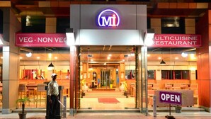 A restaurant with a sign indicating it is open, a person standing outside, and a sign for a vegetarian and non-vegetarian menu. - Hotel Matrix Inn (Rajgurunagar)