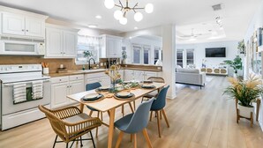 Una cocina moderna con armarios blancos, una mesa de comedor de madera y sillas azules.