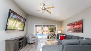 A spacious living room with a grey sofa, a grey armchair, a wooden coffee table, and a ceiling fan. - Casa De Mojave 3 Bedroom Home by RedAwning (Scottsdale)