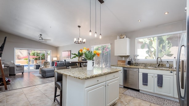 A spacious kitchen with a central island, white cabinetry, and a large window with blinds. - Casa De Mojave 3 Bedroom Home by RedAwning (Scottsdale)