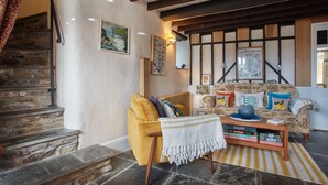 Un salon chaleureux avec un fauteuil jaune, une table basse en bois et un escalier en pierre.