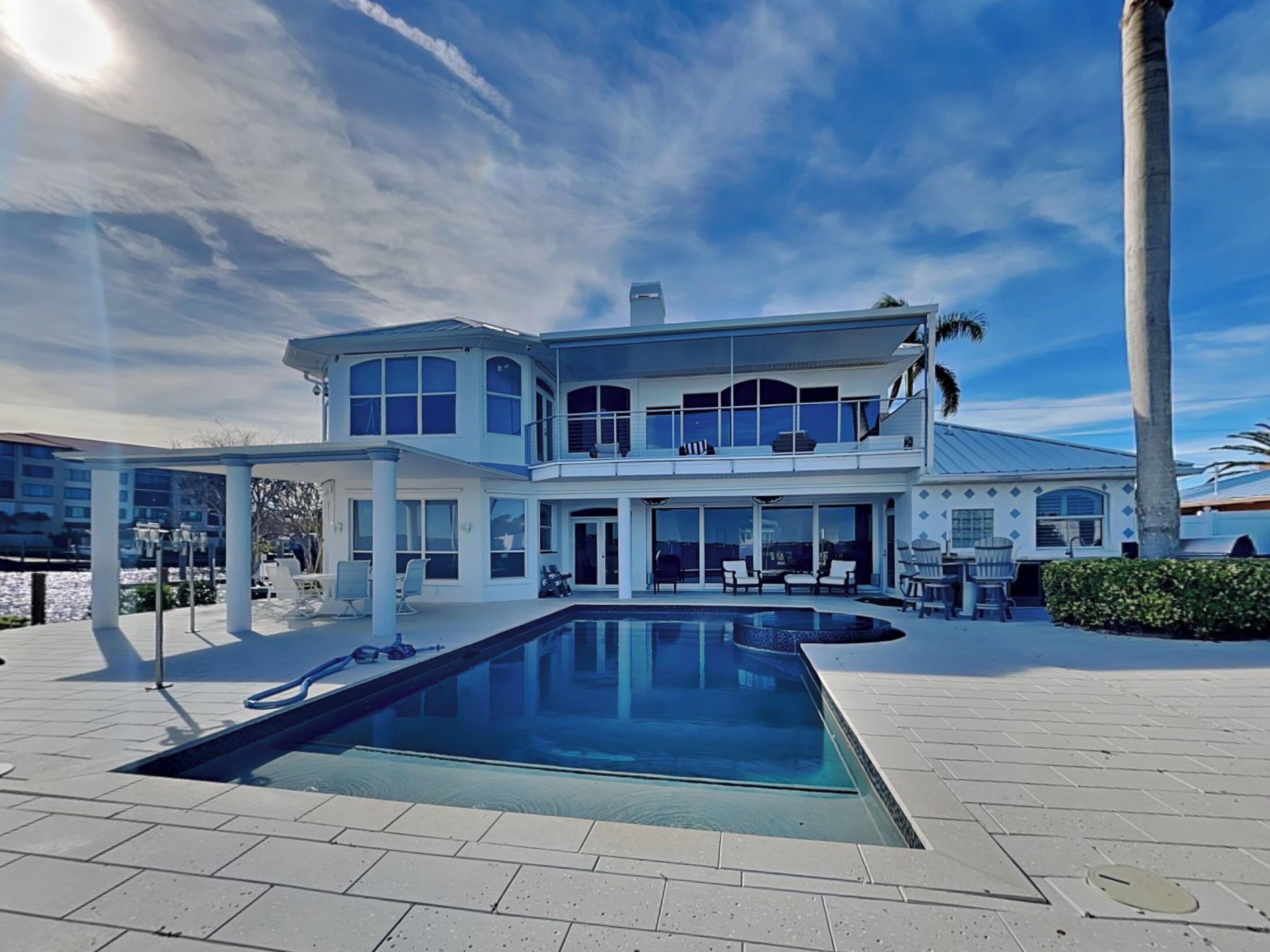 A two-story house with a swimming pool, large windows, and a balcony.