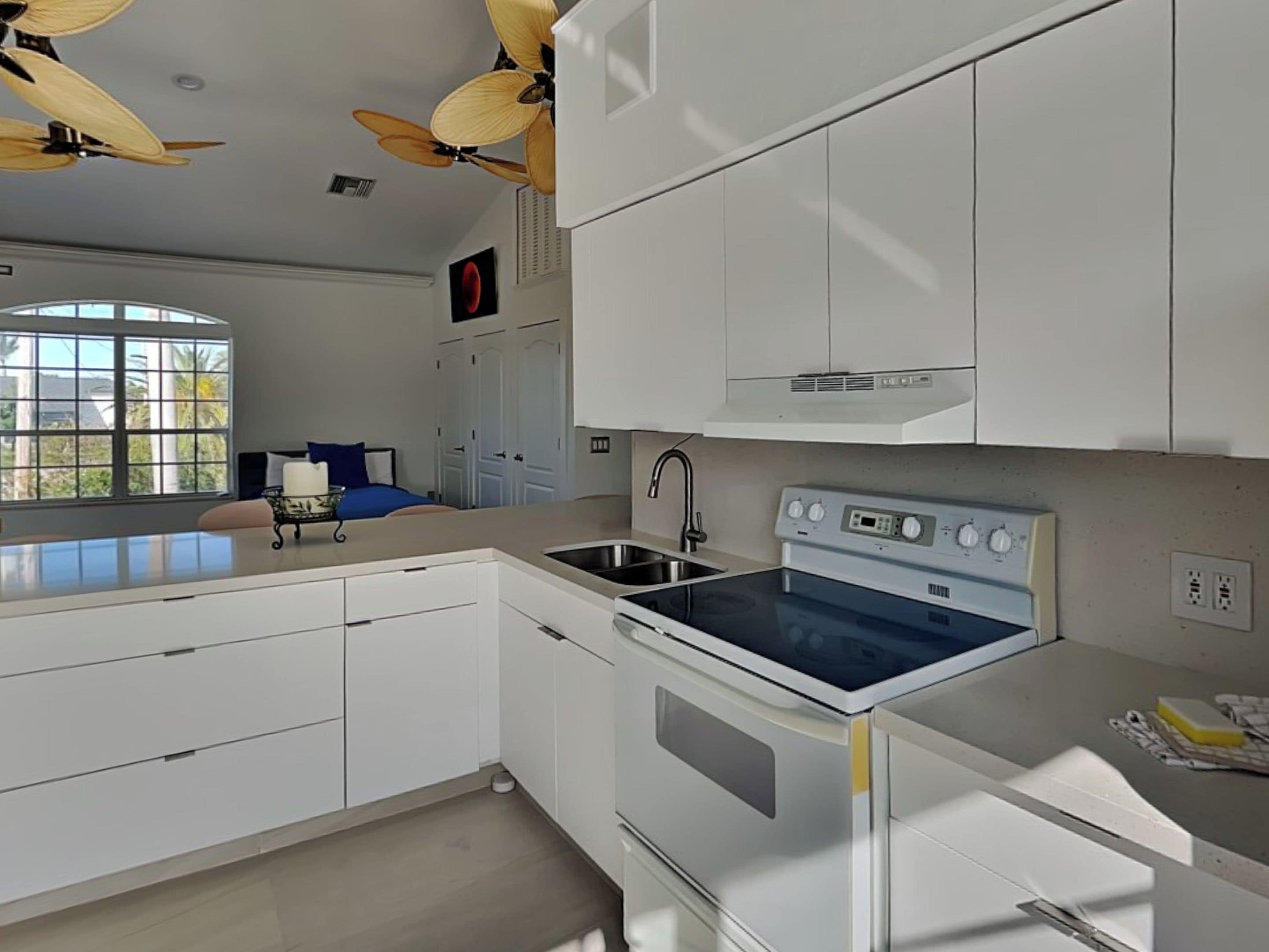 A modern kitchen with white cabinets, a built-in oven, and a sink.