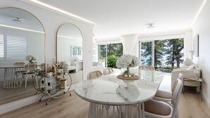 Un espace repas moderne avec une table en marbre, des chaises blanches et un grand miroir.