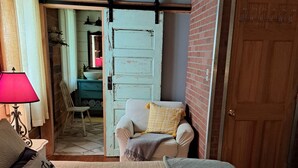 Une chambre confortable avec un lit, une chaise, une lampe et une porte donnant sur une autre pièce.
