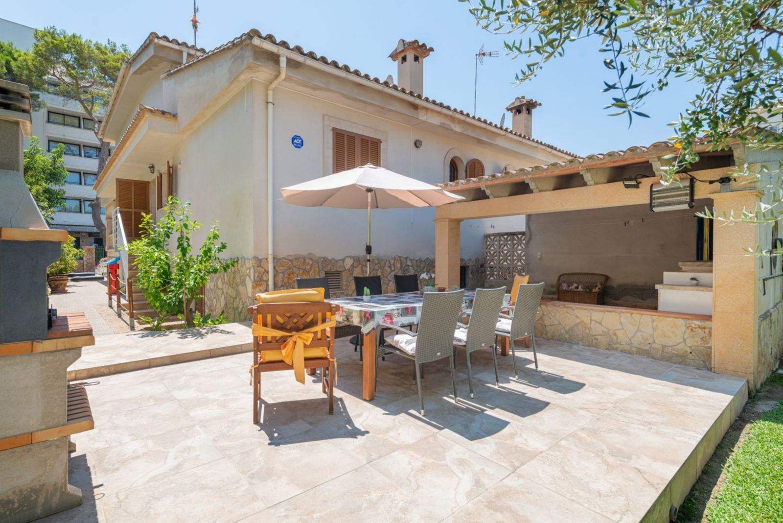 Une terrasse extérieure avec une table et des chaises, un espace barbecue et un mur en pierre.