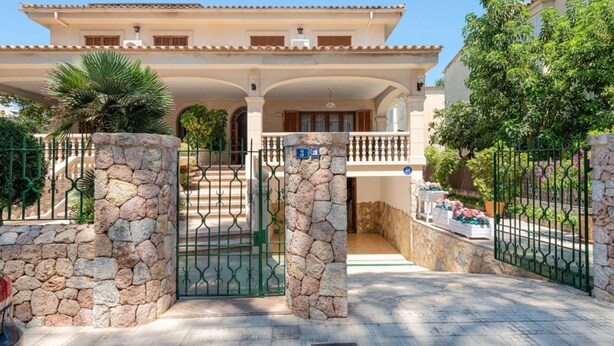 A large, two-story house with a stone gate and a balcony. - Charming Villa Near the Most Beautiful Beach in North Mallorca (Alcúdia)