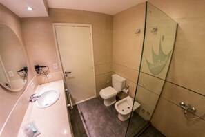 Un baño con lavamanos blanco, espejo, inodoro y bidé.
