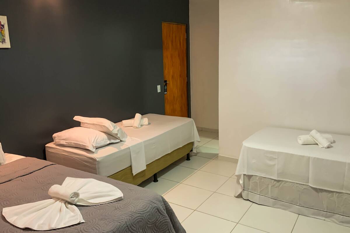 Una habitación de hotel con dos camas, una puerta de madera y una pared blanca.