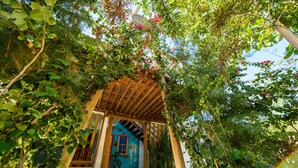 Una pérgola de madera con una puerta azul y un banco de madera debajo.