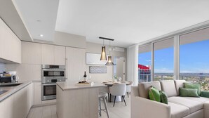 A modern kitchen with built-in appliances, a dining area with a table and chairs, and a large window offering a city view. - Luxury 3 Br- Front Intercostal View|Amazing Pools (Hollywood)