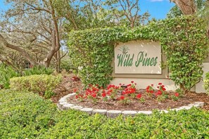 A sign reading "Wild Pines" surrounded by a garden with various plants and flowers.