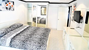 A modern bedroom with a bed, a TV, and a wardrobe. - 1 bed Condo Jomtien Beach (Pattaya)