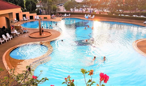 Una gran piscina coberta amb diverses línies, envoltada de gandules i una petita zona de jardí.