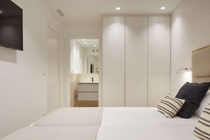 Un dormitorio con cama, televisor montado en la pared y armario con puertas correderas.