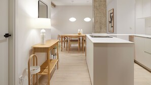 A modern kitchen with a central island, wooden dining table, and chairs.