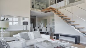 En moderne stue med en hvid sofa, et sofabord og en trappe i glas.