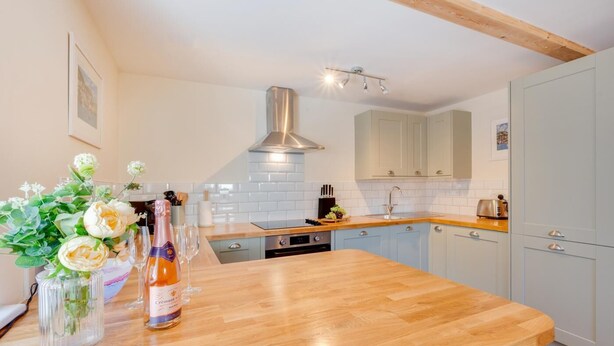 Una cocina moderna con armarios azul claro, una encimera de madera y una campana extractora de acero inoxidable.
