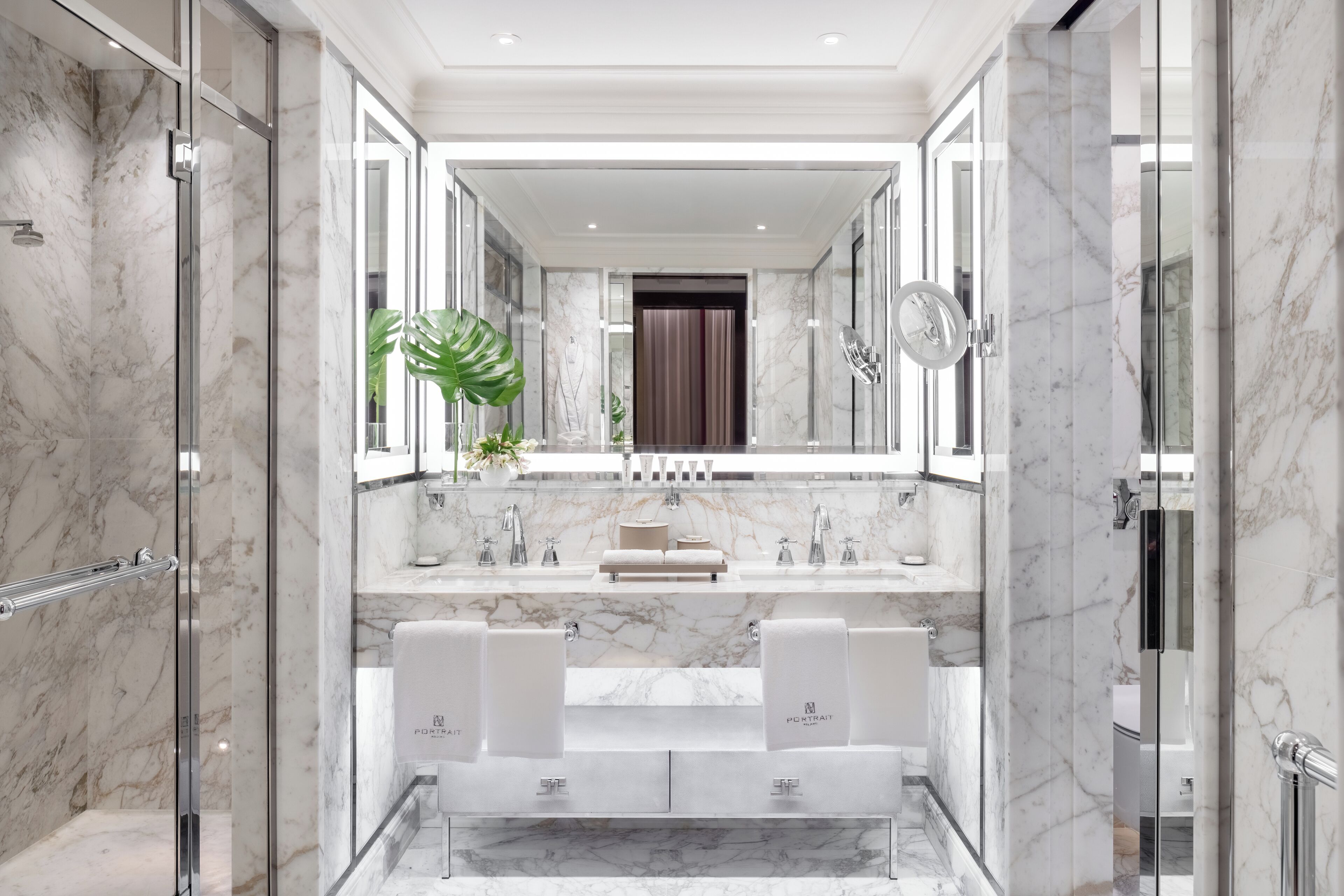 Un bagno moderno con pareti in marmo, un mobile bagno doppio e uno specchio grande.