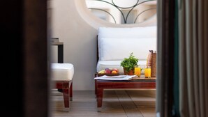 Un desayuno acogedor con una mesa de madera, frutas, una planta en maceta y una silla blanca.