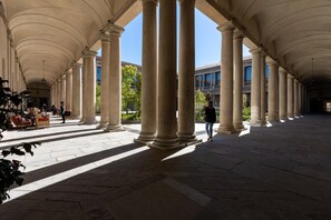 Un paseo techado con columnas, bancos y cielo despejado.