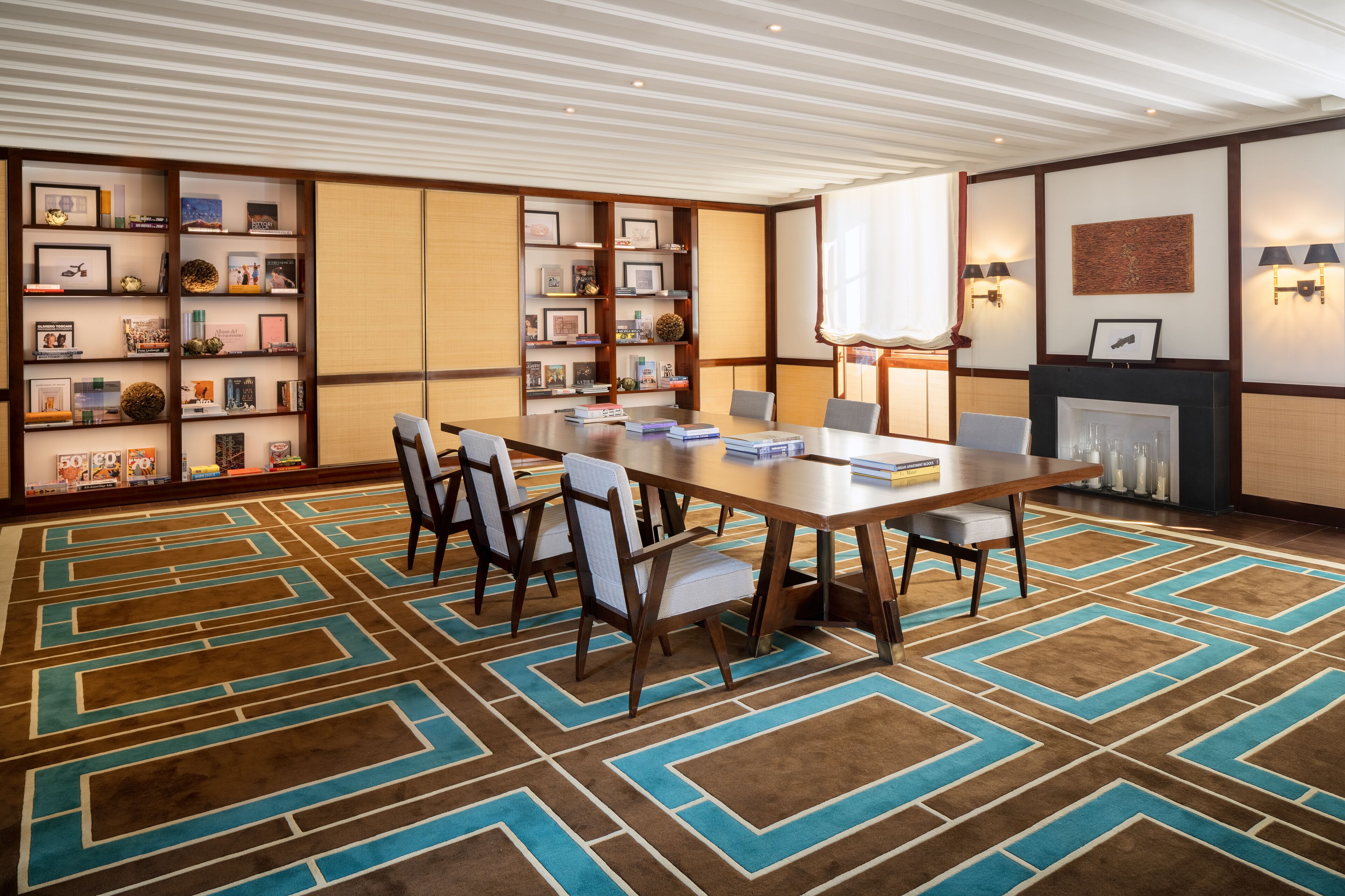 Una sala conferenze con un lungo tavolo, sedie, una libreria e un camino.