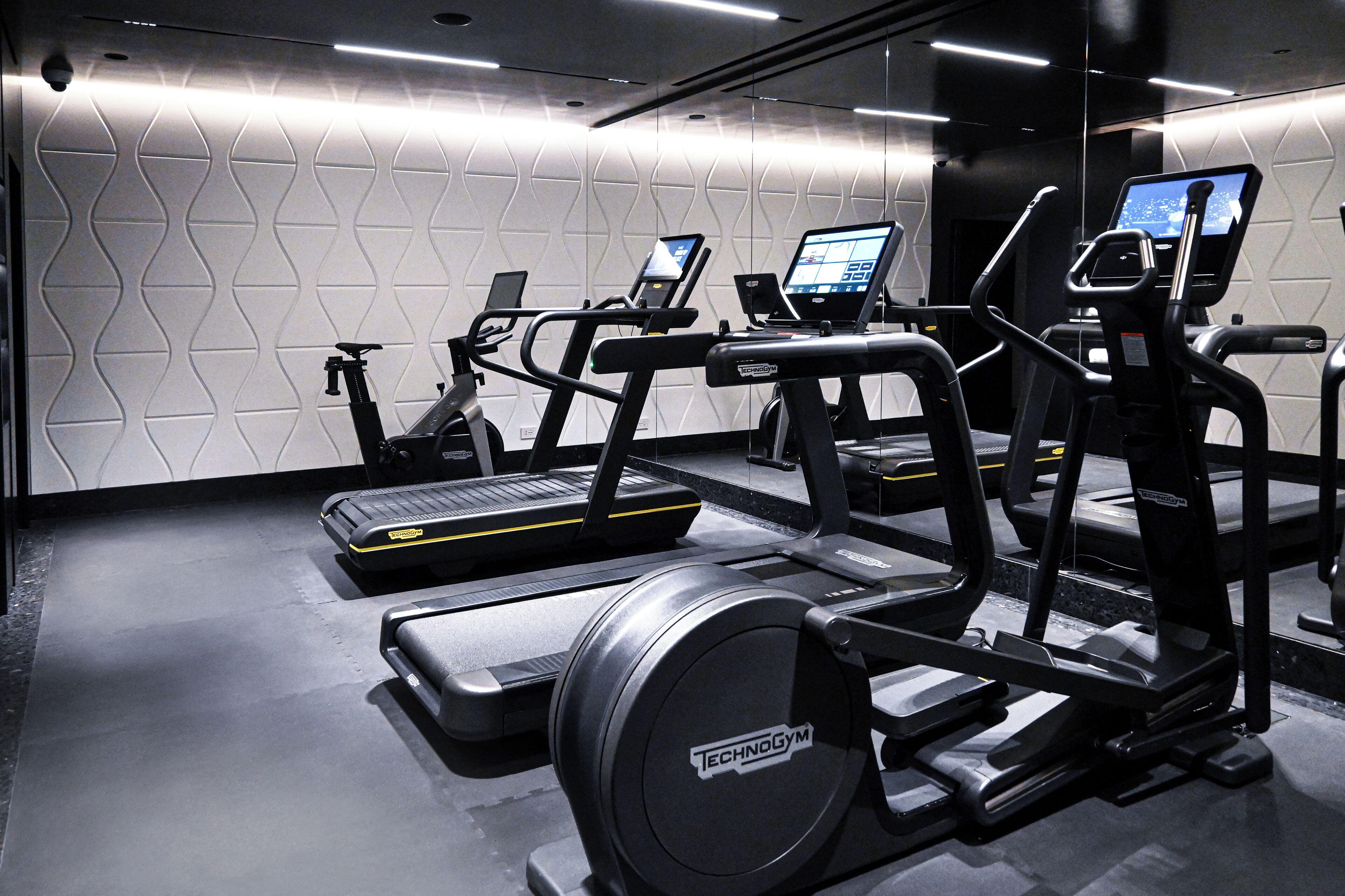 Een sportschool met loopbanden, elliptische trainers en een hometrainer.