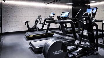 Een sportschool met loopbanden, elliptische trainers en een hometrainer.