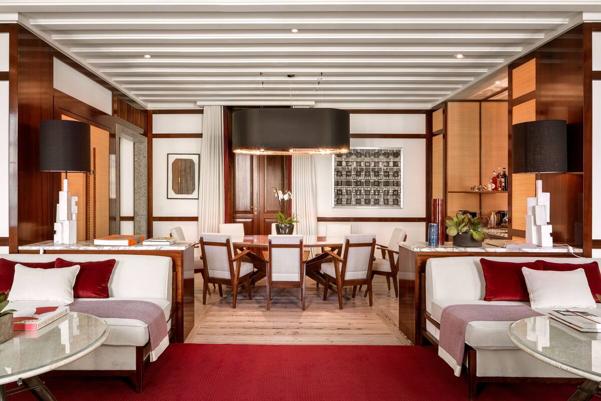 A modern dining area with a central table, surrounded by chairs, and a sofa on each side.