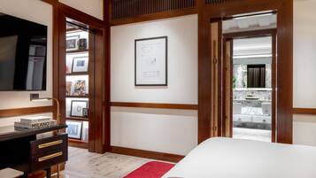A bedroom with a bed, a desk with drawers, a framed picture on the wall, and a view of a bathroom through an open door.