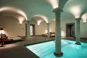 Un área de spa con piscina, sillas de descanso y columnas de piedra.