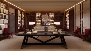 Una biblioteca con estanterías, una mesa central y dos lámparas.