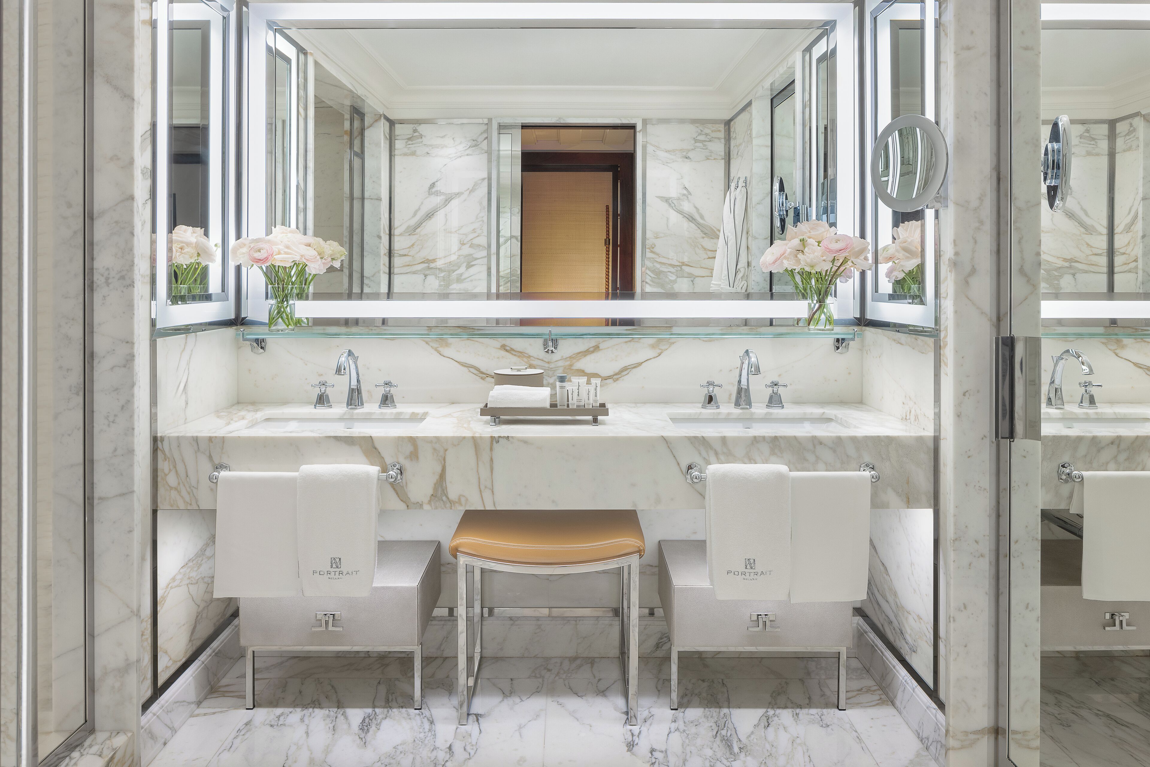 Une salle de bain avec deux lavabos, un grand miroir et un banc.