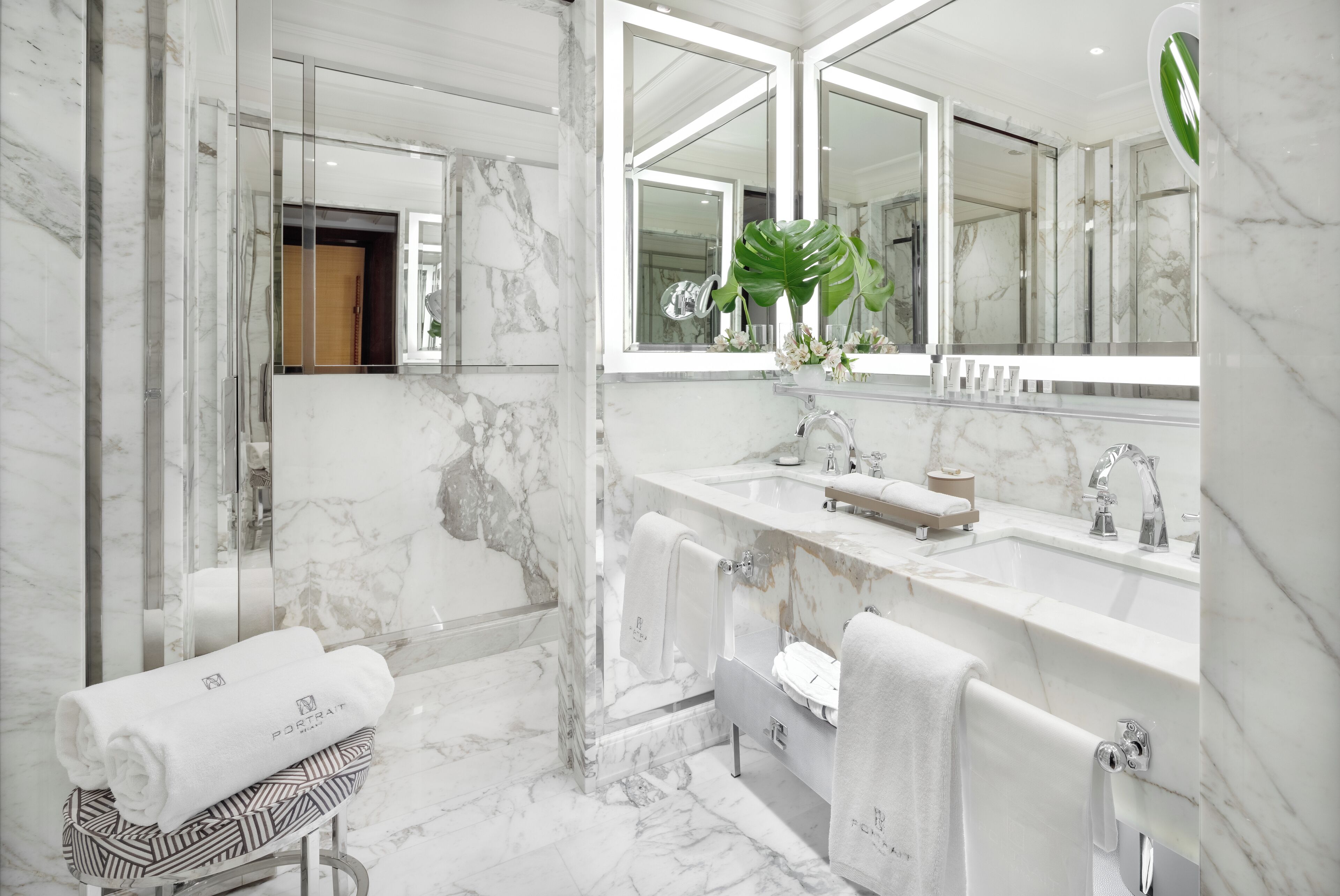 A modern bathroom with a marble floor, a large mirror, a bathtub, and a vanity with a sink and mirror.