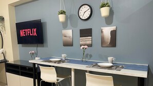 Moderni keittiö, jossa on seinään upotettu televisio, jossa näkyy Netflix, sekä seinällä oleva kello ja koriste-esineitä.