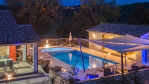 Zona de piscina con un área de estar cubierta, un edificio de piedra y vistas del paisaje circundante.