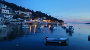 Un puerto con barcos amarrados, edificios a lo largo de la costa y un cielo sereno al atardecer.